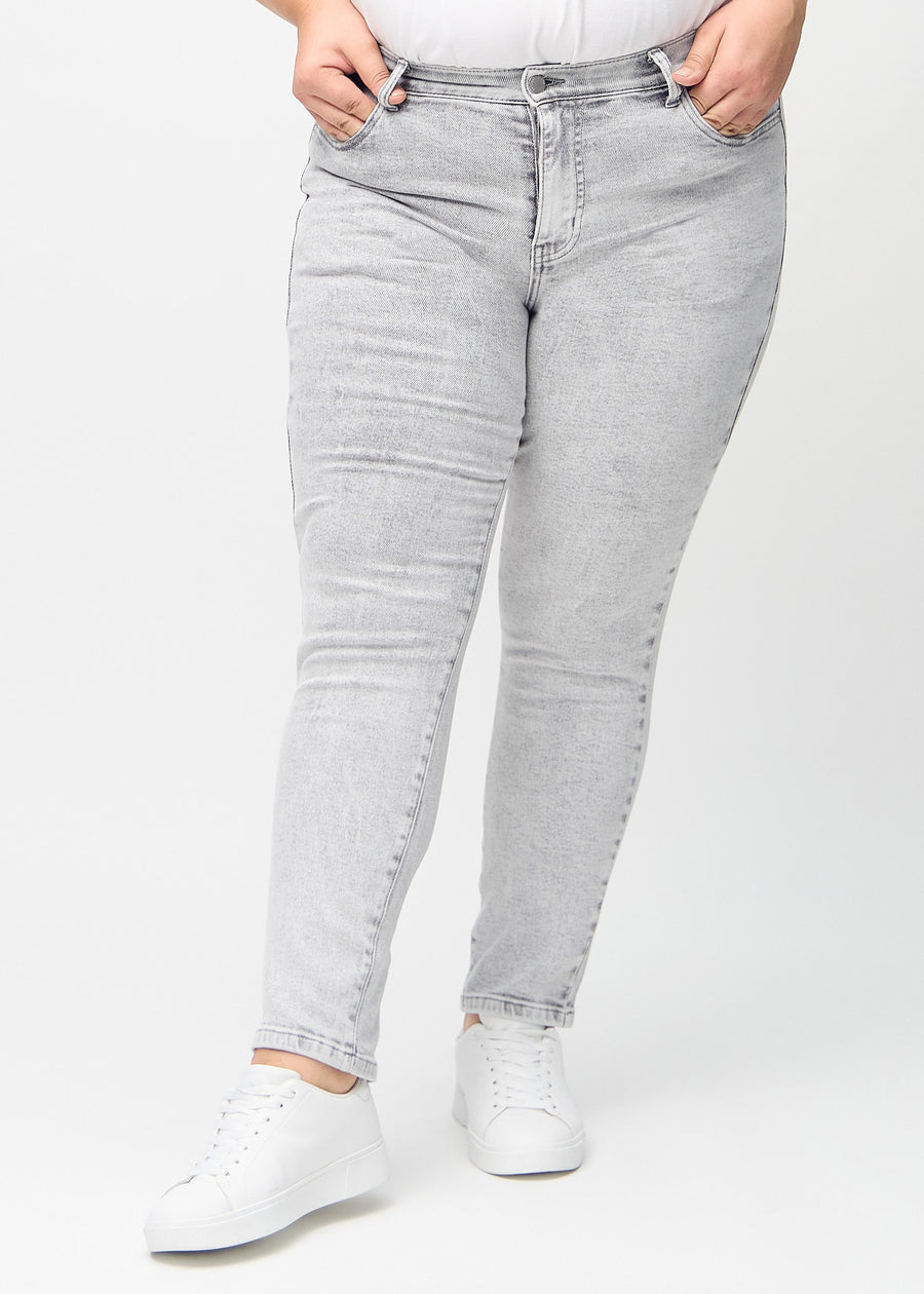 Lysegrå denim slim jeans, modelnavn Ashes, som sidder tæt til benet, dog lidt løsere ved anklen, på en plus-size model, set forfra.