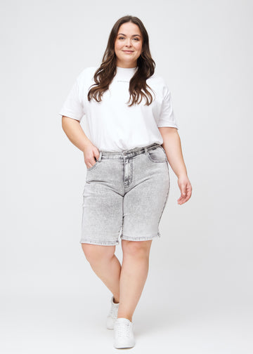 Fuldt billede af en plus-size model i lysegrå denim regular middle shorts.