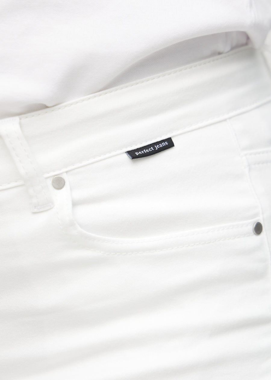 Nærbillede af hvidt jeansmateriale med Perfect Jeans logoetiket ved forlommekanten, på en plus-size model.