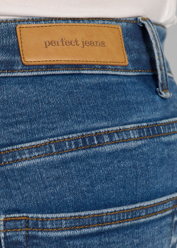 Nærbillede af mørkeblå denim med Perfect Jeans læderpatch bagpå i taljen, på en plus-size model.