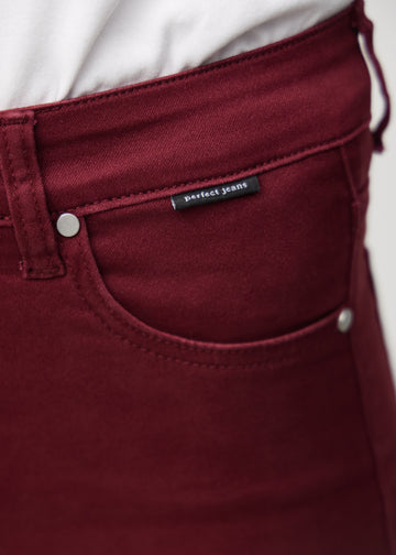 Nærbillede af rødt jeansmateriale med Perfect Jeans logoetiket ved forlommekanten.