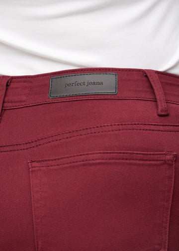 Nærbillede af rødt jeansmateriale med Perfect Jeans læderpatch bagpå i taljen, på en plus-size model.