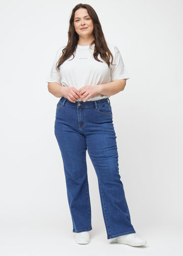Dunkelblaue Mid-Rise-Bootcut-Jeans in der Farbe Oceans. Ganzkörperansicht eines Plus-Size-Model in den Jeans.