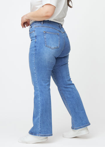 Blaue Mid-Rise-Bootcut-Jeans in der Farbe Rivers. Seitenansicht an einem Plus-Size-Model.