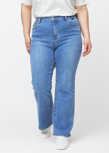 Blaue Mid-Rise-Bootcut-Jeans in der Farbe Rivers. Vorderansicht an einem Plus-Size-Model, an Hüfte und Oberschenkeln anliegend mit leicht ausgestelltem Bein.