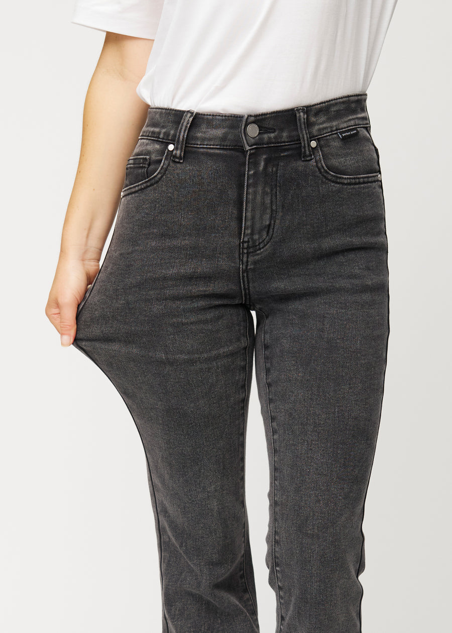 Dunkelgraue Mid-Rise-Bootcut-Jeans in der Farbe Shadows. Ein Model zieht am Jeansstoff am Oberschenkel, um den Stretch zu zeigen.