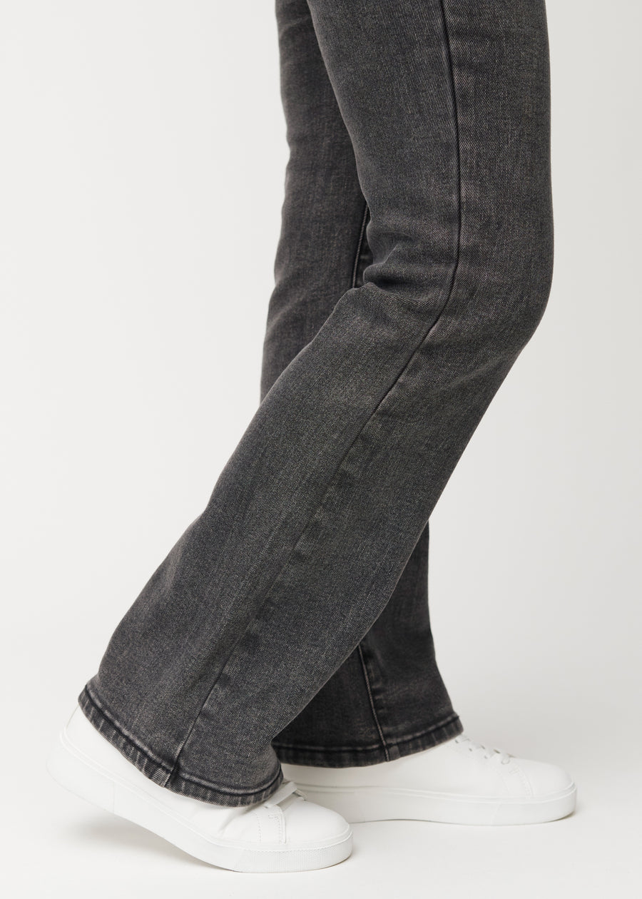 Dunkelgraue Mid-Rise-Bootcut-Jeans in der Farbe Shadows. Nahaufnahme am Knöchel eines Model, um den leichten Schlag am Beinabschluss zu zeigen.