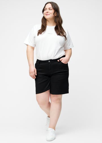 Fuldt billede af plus-size model i løse, sorte shorts i farven Ravens, der går til lige over knæet.