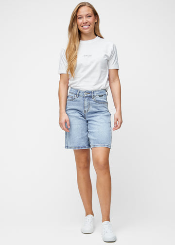 Ganzkörperbild des Models in lockeren, hellblauen Denim-Shorts in der Farbe Waves, die bis knapp über das Knie reichen.