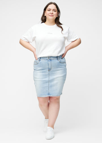 Fuldt billede af plus-size model i lyseblå, tætsiddende og knælang denimnederdel.