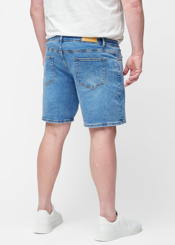 Blaue Denim-Shorts für Herren in der Farbe Rivers von hinten am Plus-Size-Modell gesehen, sodass die Länge bis knapp über das Knie sichtbar ist.