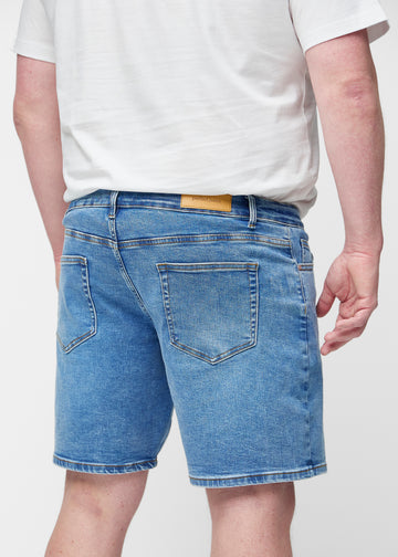 Blaue Denim-Shorts für Herren in der Farbe Rivers von hinten am Plus-Size-Modell gesehen, sodass die Länge bis knapp über das Knie sichtbar ist.