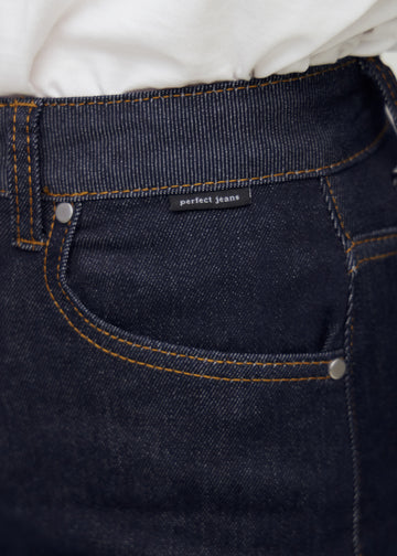 Nahaufnahme von dunkelblauem denim mit perfect jeans logoetikett ved forlommekanten.