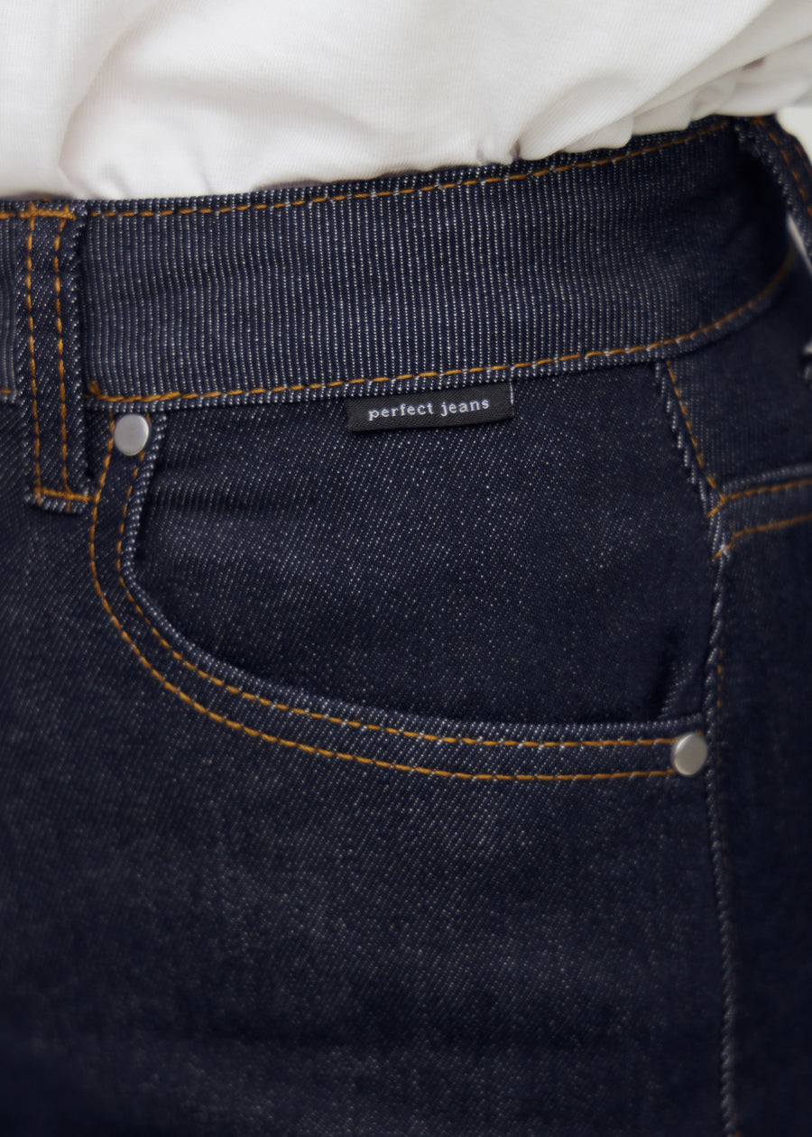 Nahaufnahme von dunkelblauem denim mit perfect jeans logoetikett ved forlommekanten.