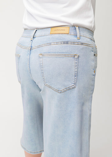 Nahaufnahme von hinten: lockere, hellblaue Waves Denim-Capris an einem Plus-Size-Model, die Passform und Details zeigen.