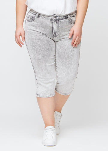 Hellgraue Denim-regular-Capris, Modellname Ashes, die gerade am Bein sitzen und bei einem Plus-Size-Model knapp unter dem Knie enden, von vorne gesehen.