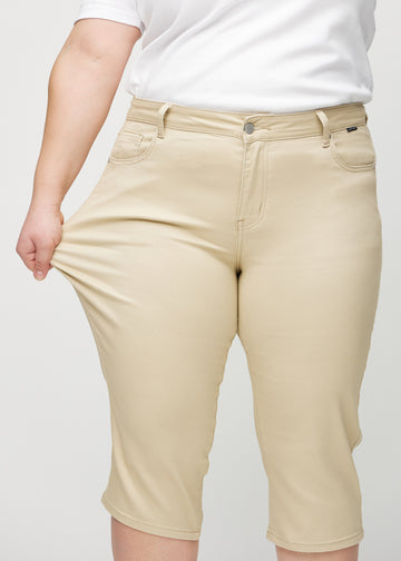 Ein Plus-Size-Model dehnt die Capris am Oberschenkel, um den Stretch zu zeigen.