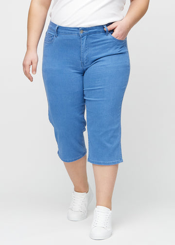 Blaue regular Capris, Modellname Geraniums, die eng am Bein anliegen und knapp unter dem Knie enden, an einem Plus-Size-Model von vorne gesehen.