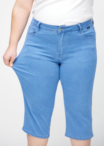 Ein Plus-Size-Model zieht die Capris am Oberschenkel auseinander, um den Stretch zu zeigen.