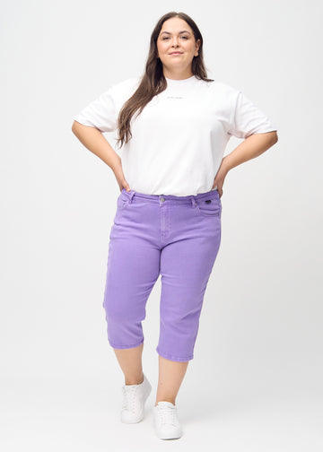 Ganzkörperbild eines Plus-Size-Models in lila regular Capris.