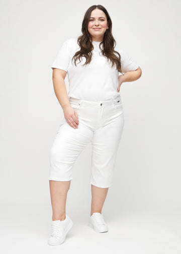 Ganzkörperbild eines Plus-Size-Models in weißen regular Capris.