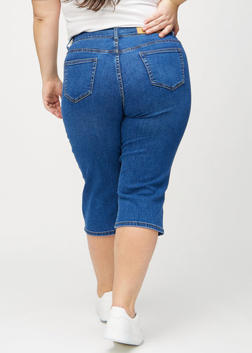 Dunkelblaue Denim-regular-Capris von hinten an einem Plus-Size-Model gesehen, sodass man das gesamte Produkt sehen kann.