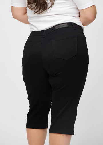 Schwarze regular Capris von hinten aus der Nähe an einem Plus-Size-Model gesehen, um Details zu zeigen.
