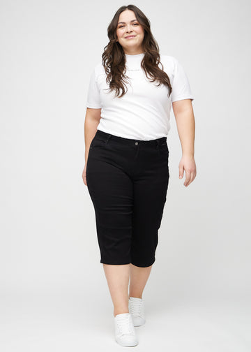 Ganzkörperbild eines Plus-Size-Models in schwarzen regular Capris.