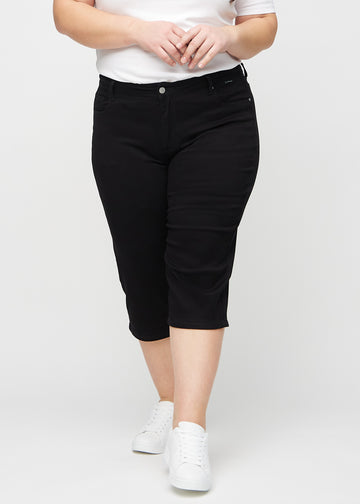 Schwarze regular Capris, Modellname Ravens, die eng am Bein anliegen und knapp unter dem Knie enden, an einem Plus-Size-Model von vorne gesehen.