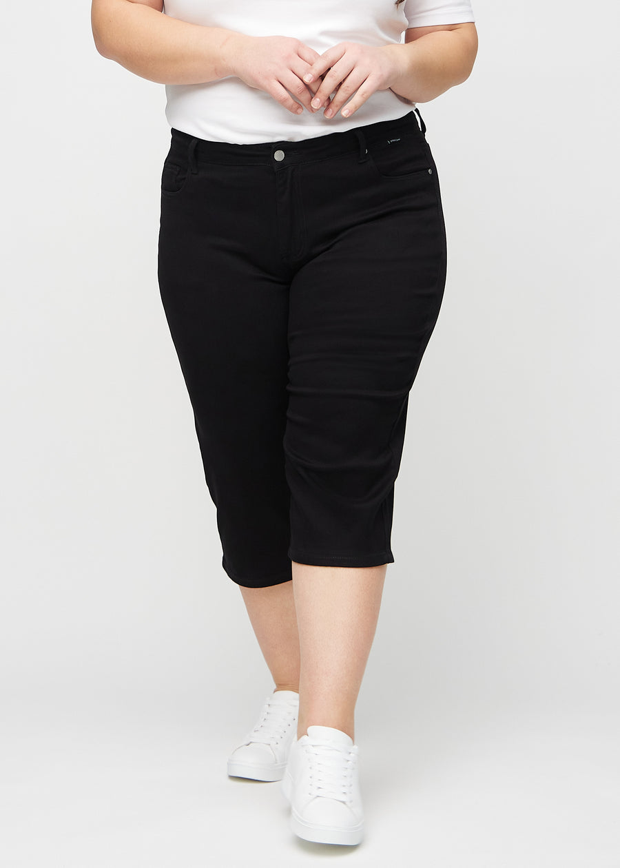 Schwarze regular Capris, Modellname Ravens, die eng am Bein anliegen und knapp unter dem Knie enden, an einem Plus-Size-Model von vorne gesehen.
