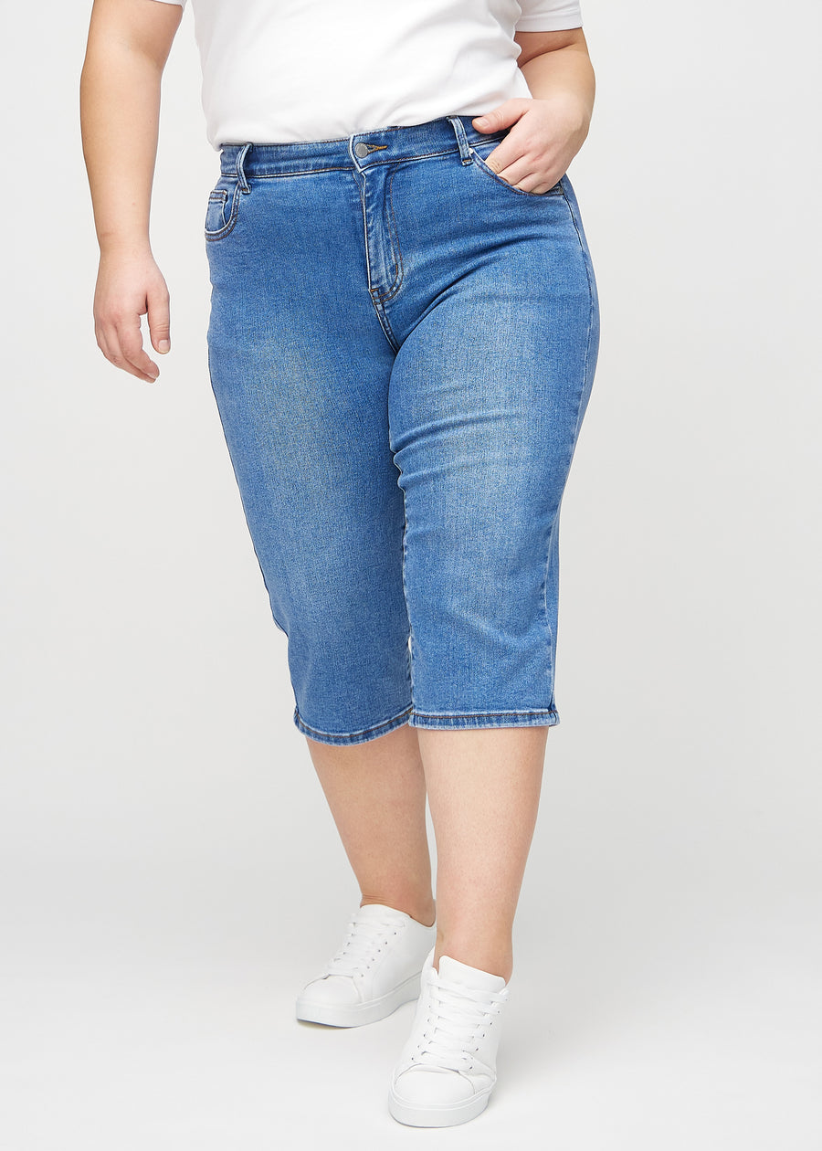 Denim-regular-Capris, Modellname Rivers, die eng am Bein anliegen und direkt unter dem Knie enden, an einem Plus-Size-Model von vorne gesehen.