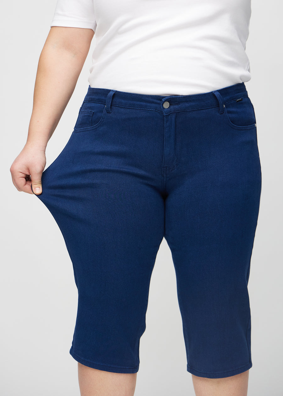 Das Plus-Size-Model zieht die Capris am Oberschenkel, um den Stretch zu zeigen.