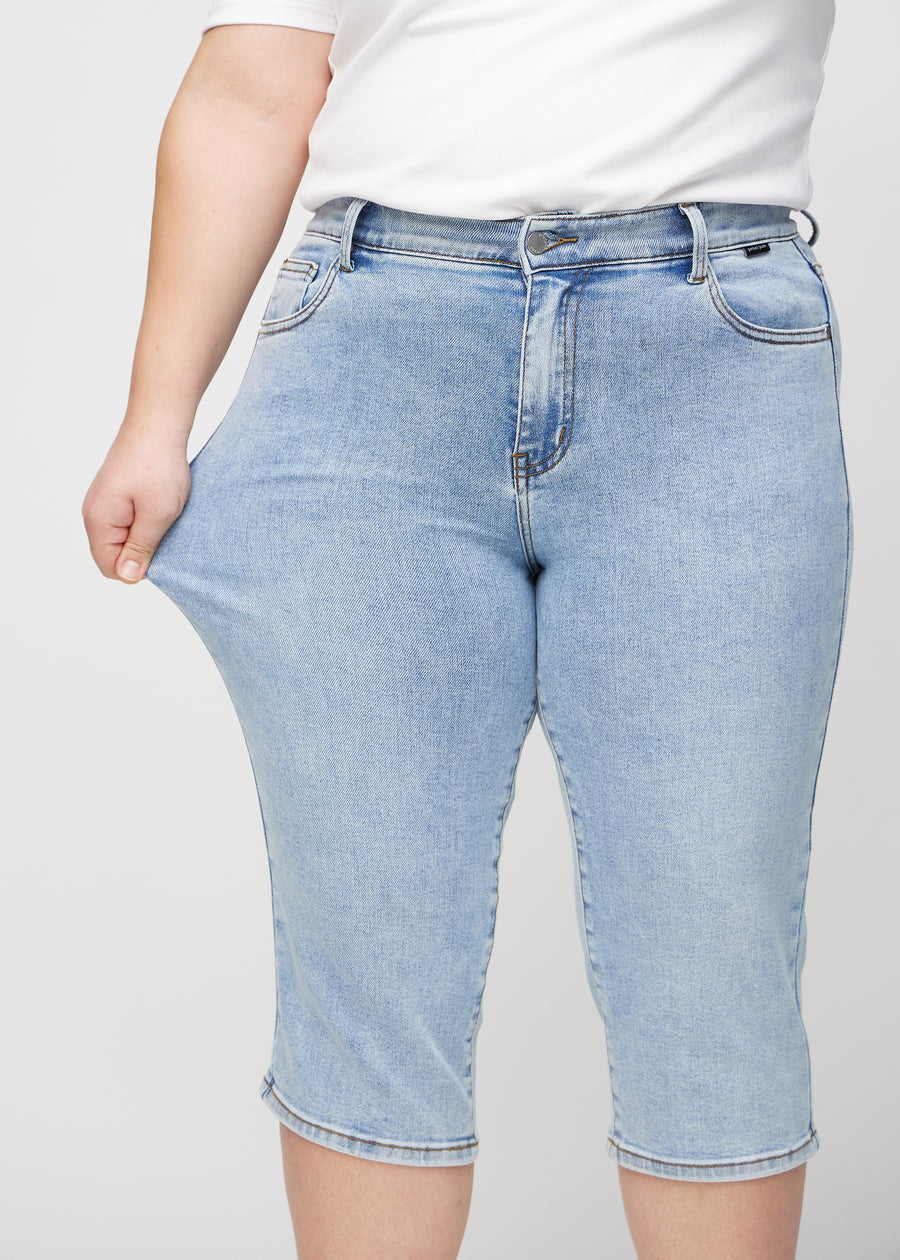 Das Plus-Size-Model zieht die Capris am Oberschenkel auseinander, um den Stretch zu zeigen.