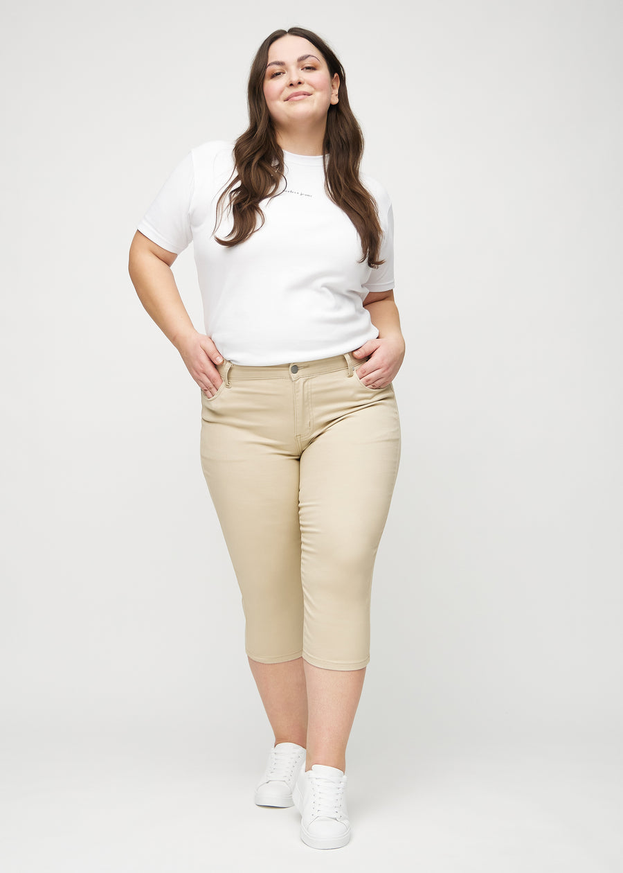 Ganzkörperbild eines Plus-Size-Models in beigen skinny Capris.