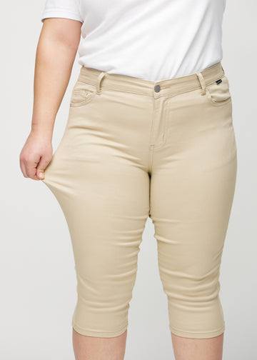 Das Plus-Size-Model dehnt die Capris am Oberschenkel, um den Stretch zu zeigen.