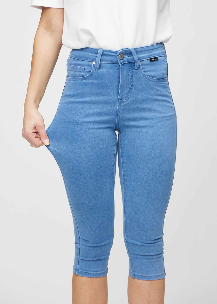 Skinny-Capris für Damen in blauem Jeansstoff, Farbe Geraniums. Ein Model dehnt den Stoff, um den Stretch zu zeigen.