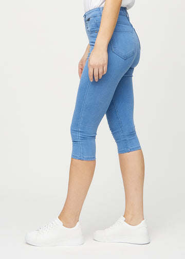 Skinny-Capris für Damen in blauem Jeansstoff, Farbe Geraniums. Seitenansicht an einem Model, die figurbetonte Passform ist zu sehen.