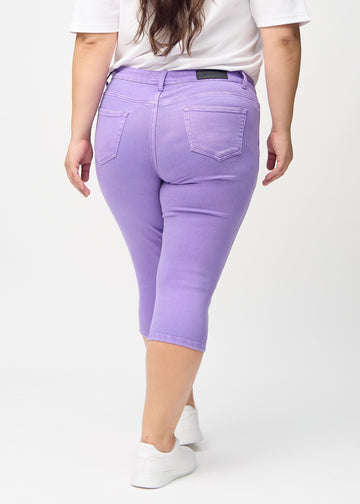 Skinny-Capris für Damen in pastellviolettem Jeansstoff, Farbe Lavenders. Rückansicht an einem Plus-Size-Model, zeigt die Passform und Gesäßtaschen.