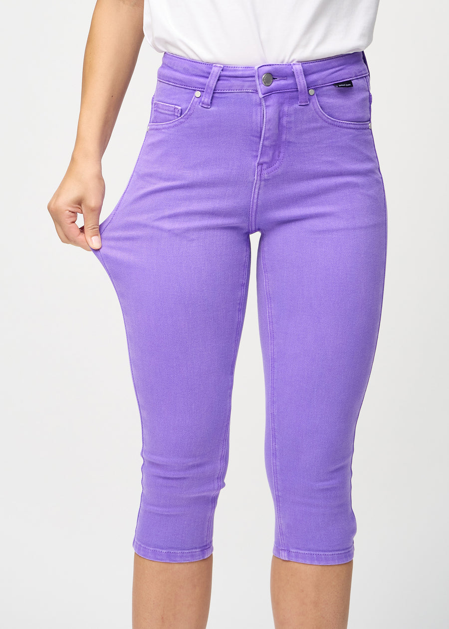 Skinny-Capris für Damen in pastellviolettem Jeansstoff, Farbe Lavenders. Ein Model dehnt den Stoff, um den Stretch zu zeigen.