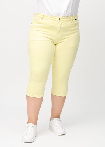 Hellgelbe skinny Capris, Modellname Lemonades, die eng am Bein anliegen, an einem Plus-Size-Model, von vorne gesehen.