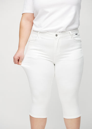Skinny-Capris für Damen in weißem Jeansstoff, Farbe Marguerites. Ein Plus-Size-Model dehnt den Stoff, um den Stretch zu zeigen.