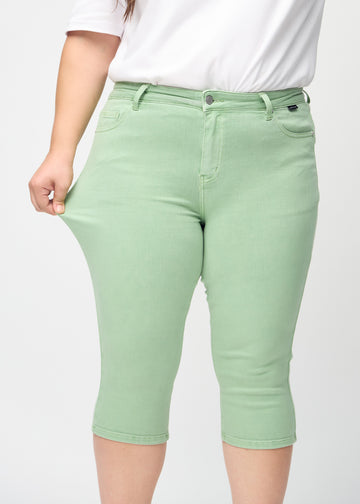 Skinny-Capris für Damen in pastellgrünem Jeansstoff, Farbe Mints. Ein Plus-Size-Model dehnt den Stoff, um den Stretch zu zeigen.