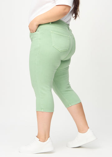 Skinny-Capris für Damen in pastellgrünem Jeansstoff, Farbe Mints. Seitenansicht an einem Plus-Size-Model, die figurbetonte Passform ist zu sehen.