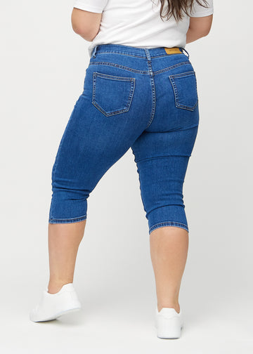 Dunkle Denim-skinny-Capris von hinten an einem Plus-Size-Model gesehen, damit man das gesamte Produkt sehen kann.