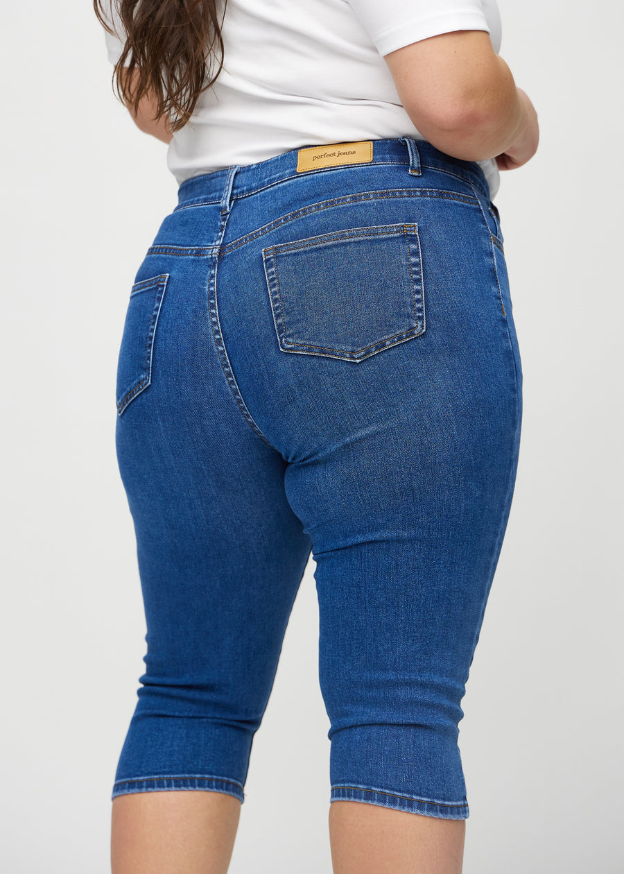 Dunkle Denim-skinny-Capris von hinten in Nahaufnahme an einem Plus-Size-Model, um Details zu zeigen.