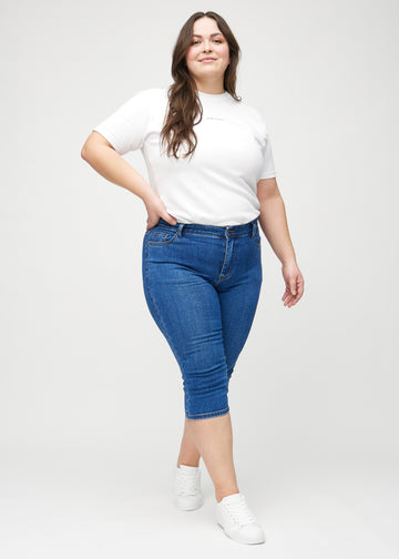 Ganzkörperbild eines Plus-Size-Models in dunklen Denim-skinny-Capris.