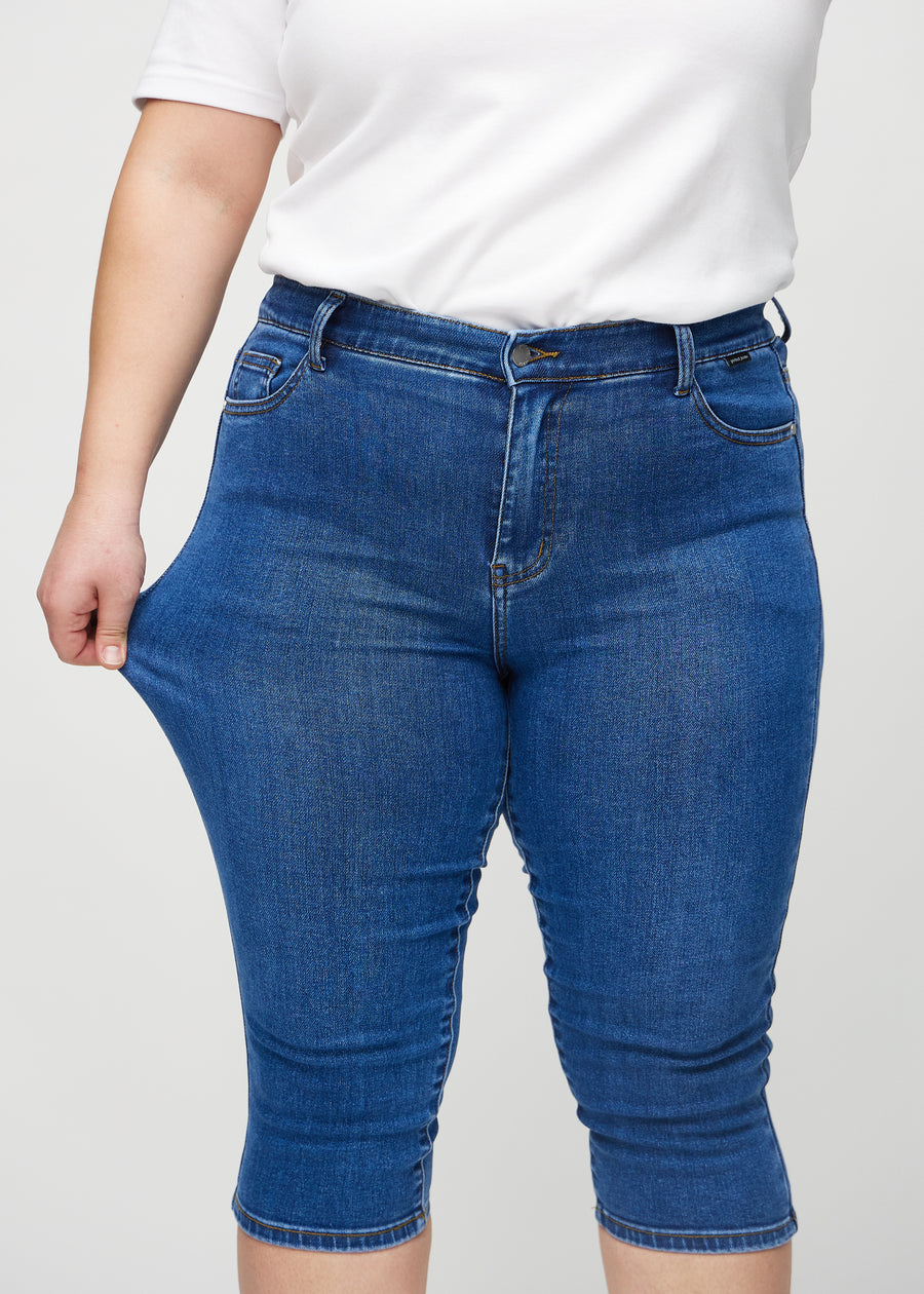 Das Plus-Size-Model zieht die Capris am Oberschenkel, um den Stretch zu zeigen.
