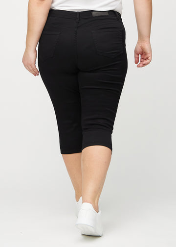 Schwarze skinny Capris von hinten an einem Plus-Size-Model gesehen, sodass man das gesamte Produkt sehen kann.