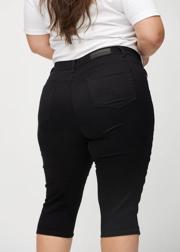 Schwarze skinny Capris von hinten aus der Nähe an einem Plus-Size-Model gesehen, um Details zu zeigen.