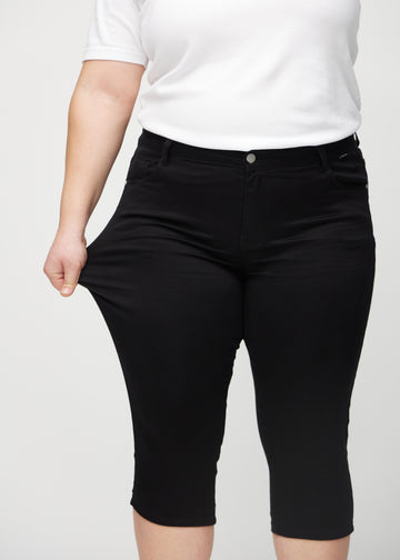 Das Plus-Size-Model zieht die Capris am Oberschenkel auseinander, um den Stretch zu zeigen.